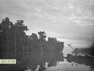 At dawn, a dusting plane spreads insecticide on the Tennessee River to destroy malaria carrying mosquitoes